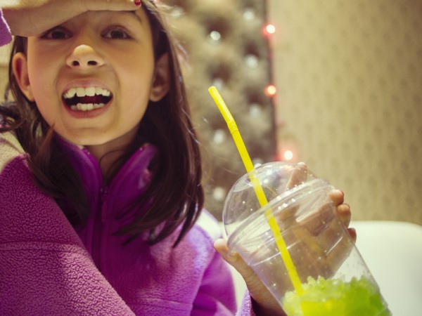 Mixed race girl with brain freeze drinking frozen drink