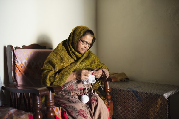Older woman knitting baby clothes