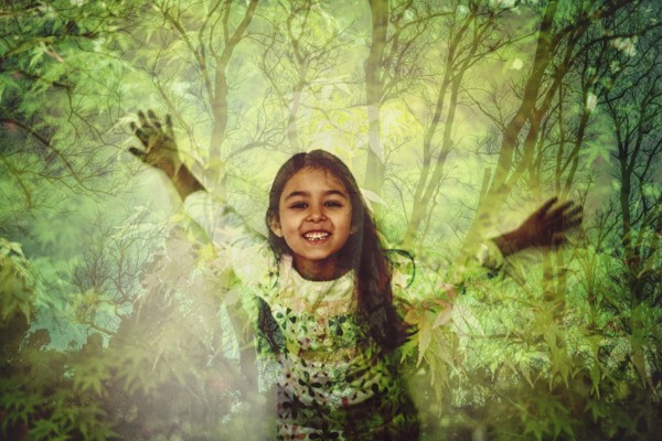 Mixed race girl standing in forest projection