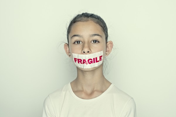 Mixed race girl wearing fragile sticker over mouth