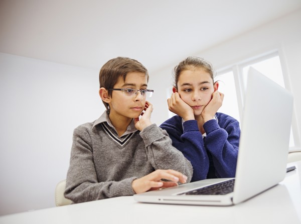 Mixed race children using laptop at desk