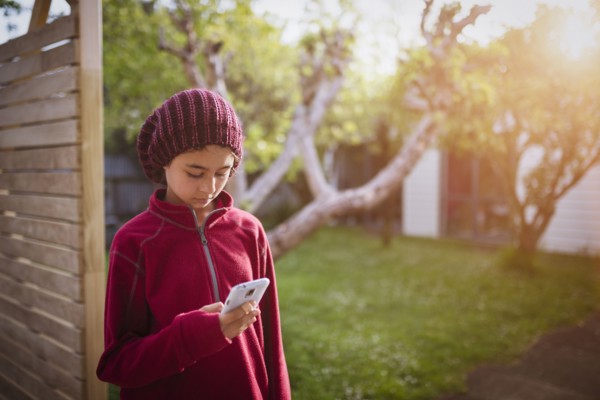 Mixed race girl using cell phone in backyard