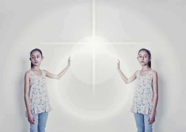 Mirror image of mixed race girl reaching for light