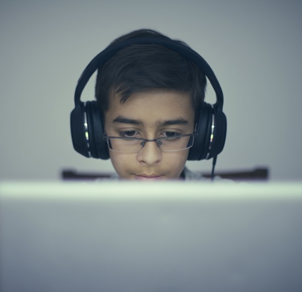 Mixed Race boy listening to laptop with headphones