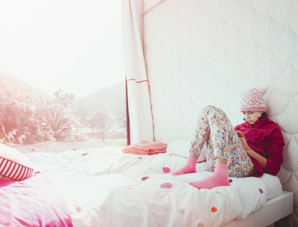 Mixed Race girl sitting on bed texting on cell phone