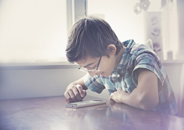 Smiling Mixed Race boy texting on cell phone