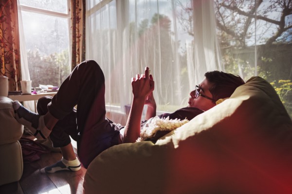 Mixed Race boy texting on cell phone near window
