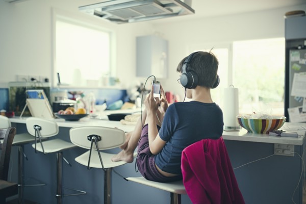 Mixed race boy sitting in kitchen listening to cell phone