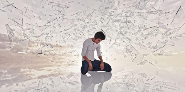 Shards of glass surrounding kneeling man