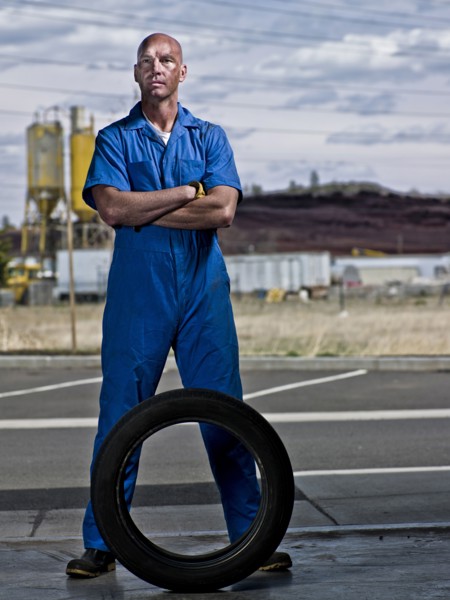 Serious mechanic standing with tire