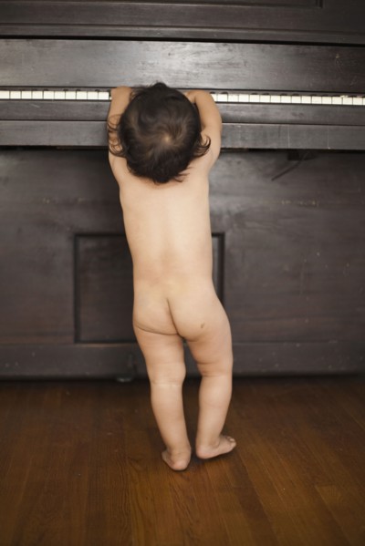Naked mixed race baby playing piano