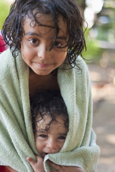 Wet mixed race boy and brother wrapped in towel