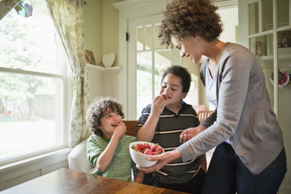 Mother giving sons snack of strawberries
