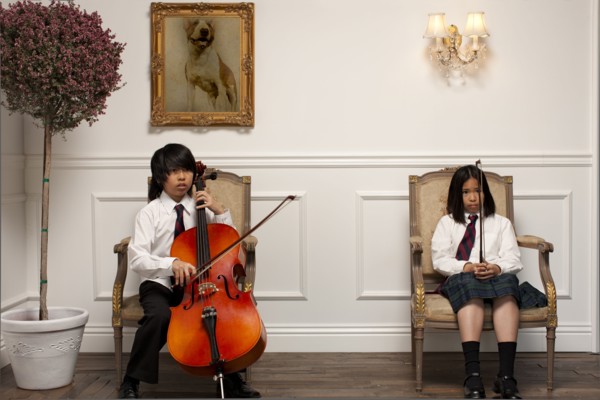 Vietnamese children with musical instruments sitting on elegant chairs