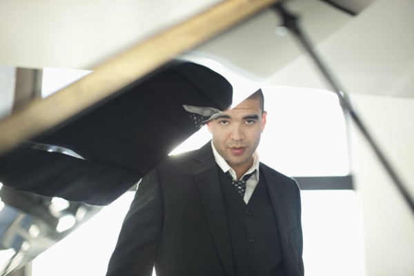Mixed race businessman standing behind piano
