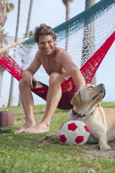 Caucasian man relaxing in hammock petting dog