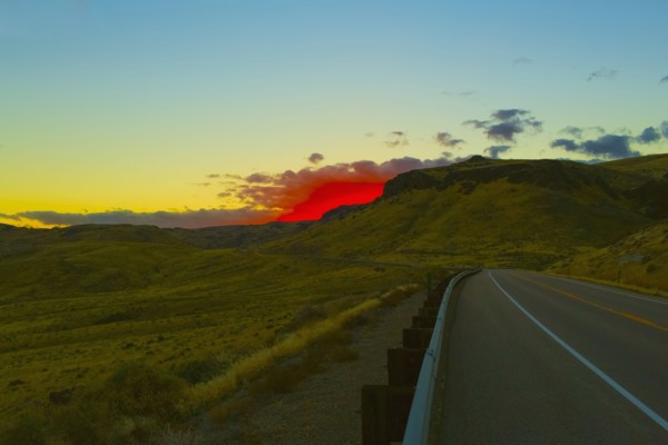 Red sunset over rural road and hillside