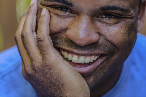 Close up of smiling Black man resting chin in hand