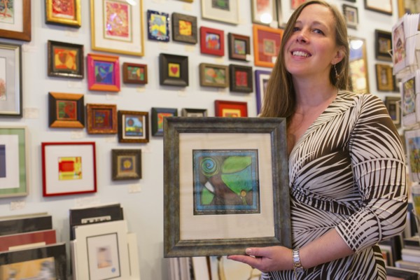 Caucasian artist holding artwork in gallery