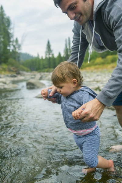 Father helping daughter walk in river