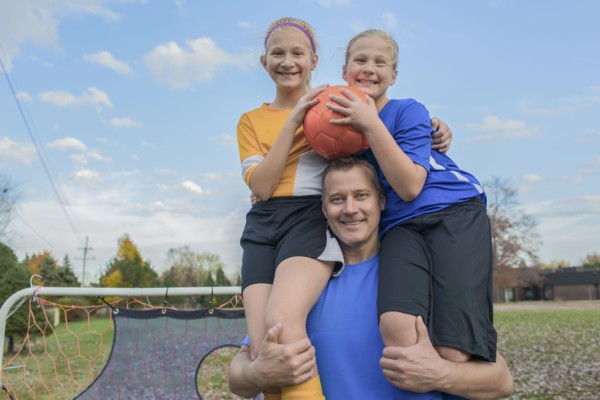 Caucasian father holding daughters in field