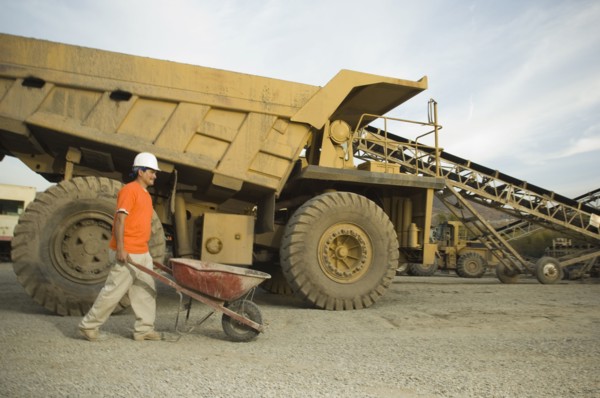 Hispanic man pushing wheelbarrow at gravel plant