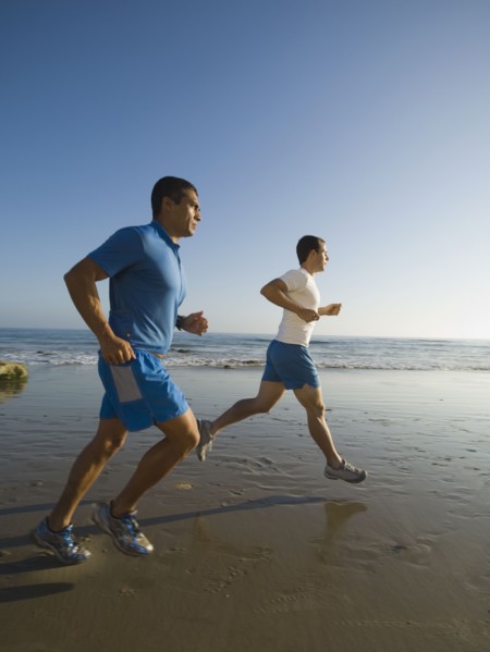 Hispanic men running at beach