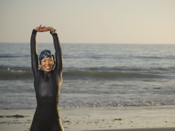 Asian woman stretching in wetsuit and goggles