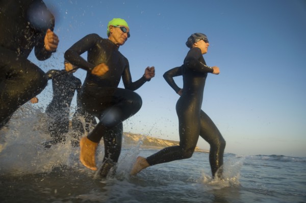 Multi-ethnic swimmers running in surf