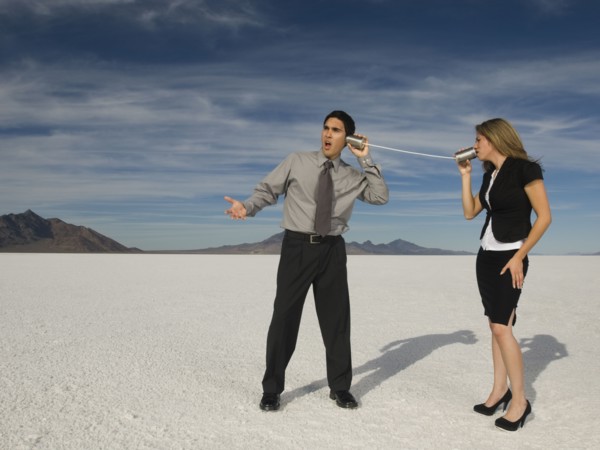 Hispanic businesspeople talking on can and string telephone
