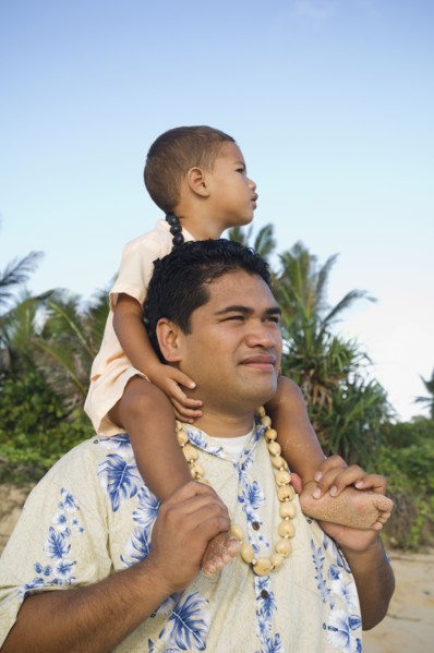 Pacific Islander father with son on shoulders at beach