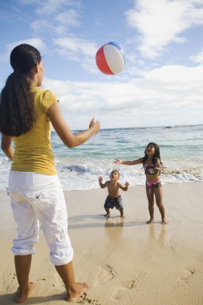 Pacific Islander mother and children playing with beach ball