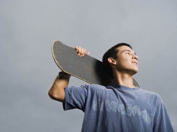 Mixed race teenager standing with skateboard
