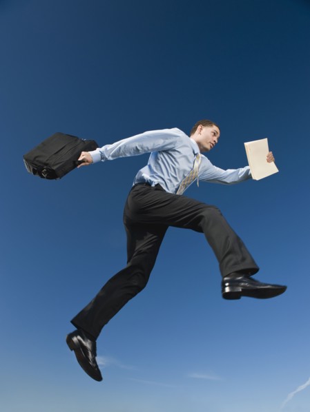 African businessman carrying briefcase in mid-air