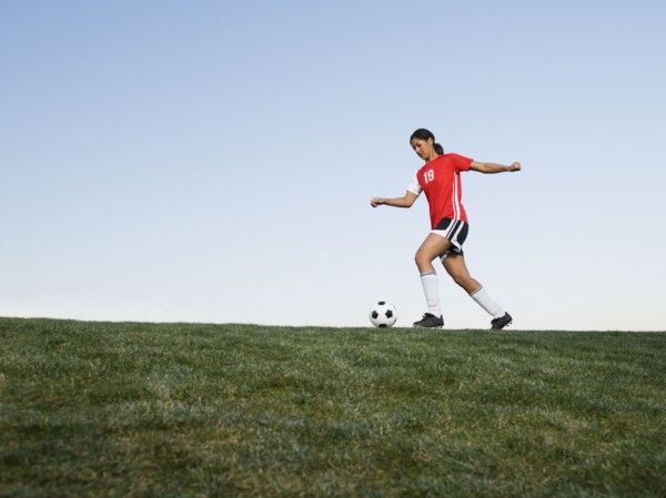 Mixed race woman kicking soccer ball