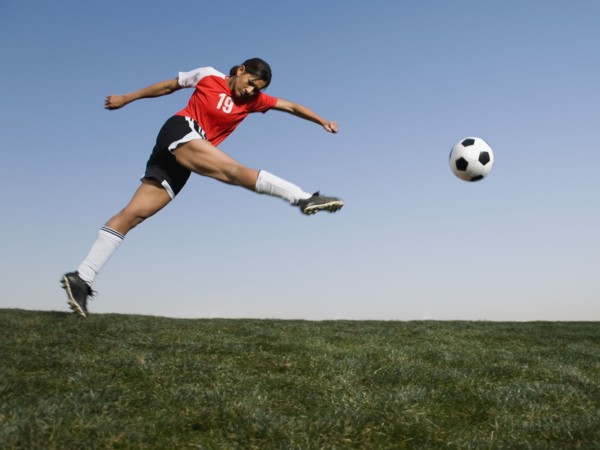 Mixed race woman kicking soccer ball
