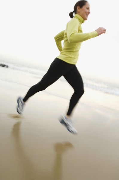 Hispanic woman running on beach