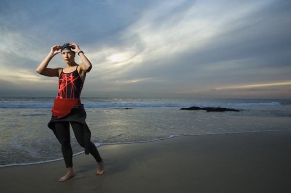 Hispanic woman in wetsuit on beach