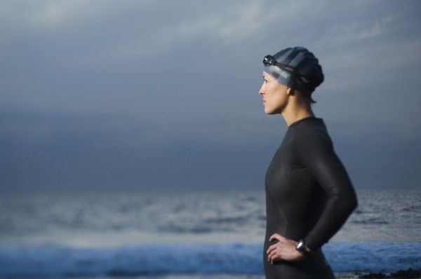 Hispanic woman in wetsuit on beach