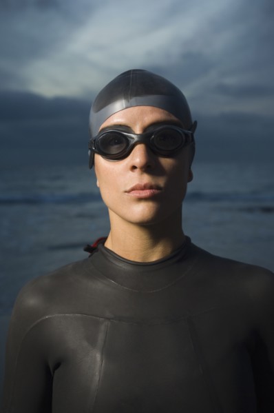 Hispanic woman in wetsuit on beach