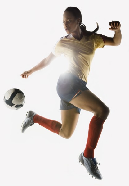Mixed race soccer player kicking soccer ball in mid-air