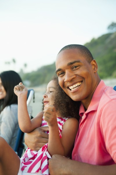 Smiling father holding daughter on beach
