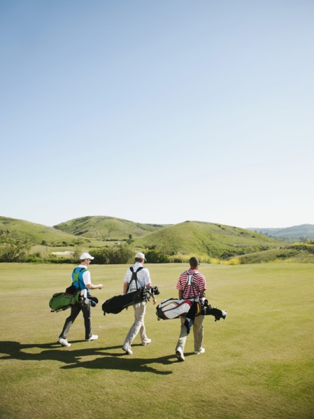 Men carrying golf bags on golf course