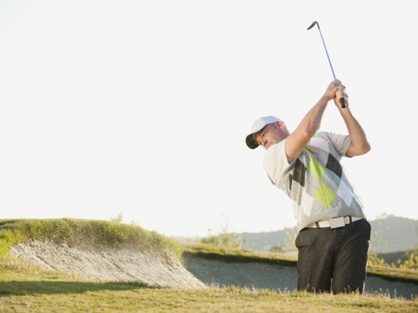 Caucasian golfer hitting ball out of bunker