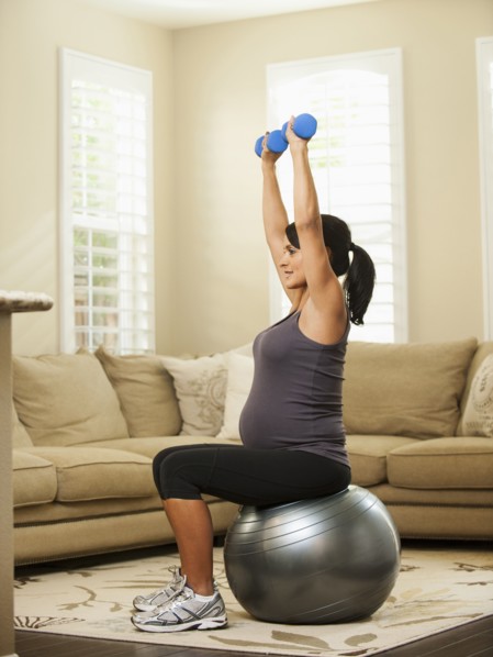 Pregnant Hispanic woman lifting weights