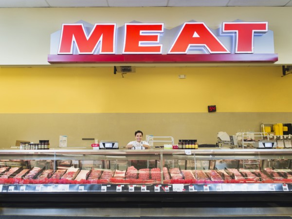 Hispanic butcher at meat counter of grocery store