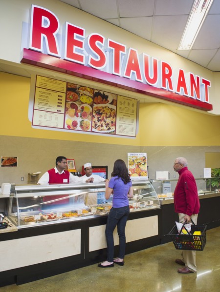 Businessman and chef serving customers at restaurant counter