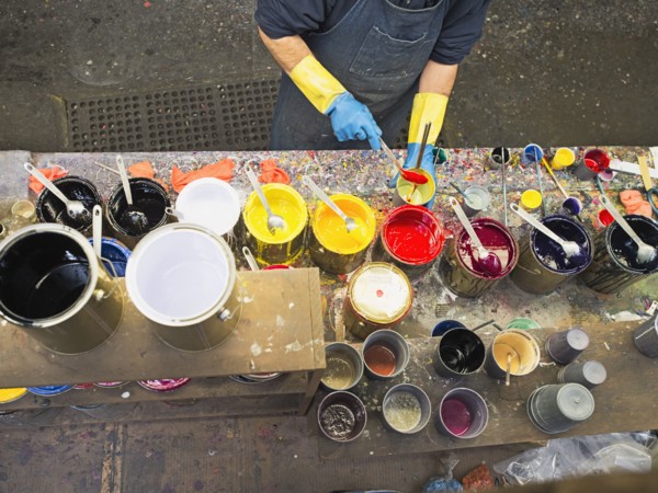 Hispanic worker mixing paint in workshop