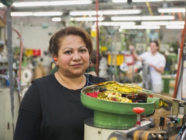 Hispanic worker operating machinery in textile factory