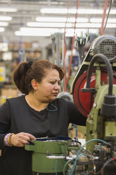 Hispanic worker operating machinery in textile factory
